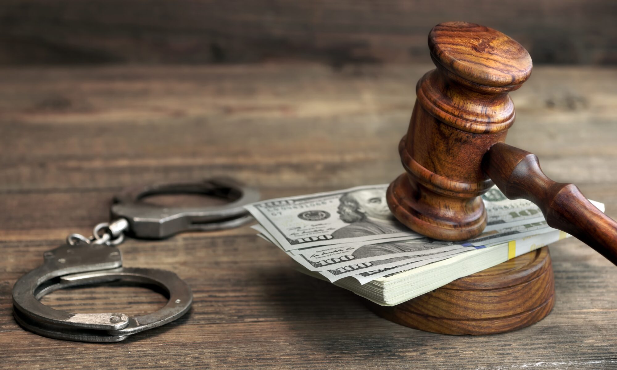USA Dollar Money Cash, Real Handcuffs And Judge Gavel On Rough Wood Background. Concept For Arrest, Corruption, Bail, Crime, Bribing or Fraud.